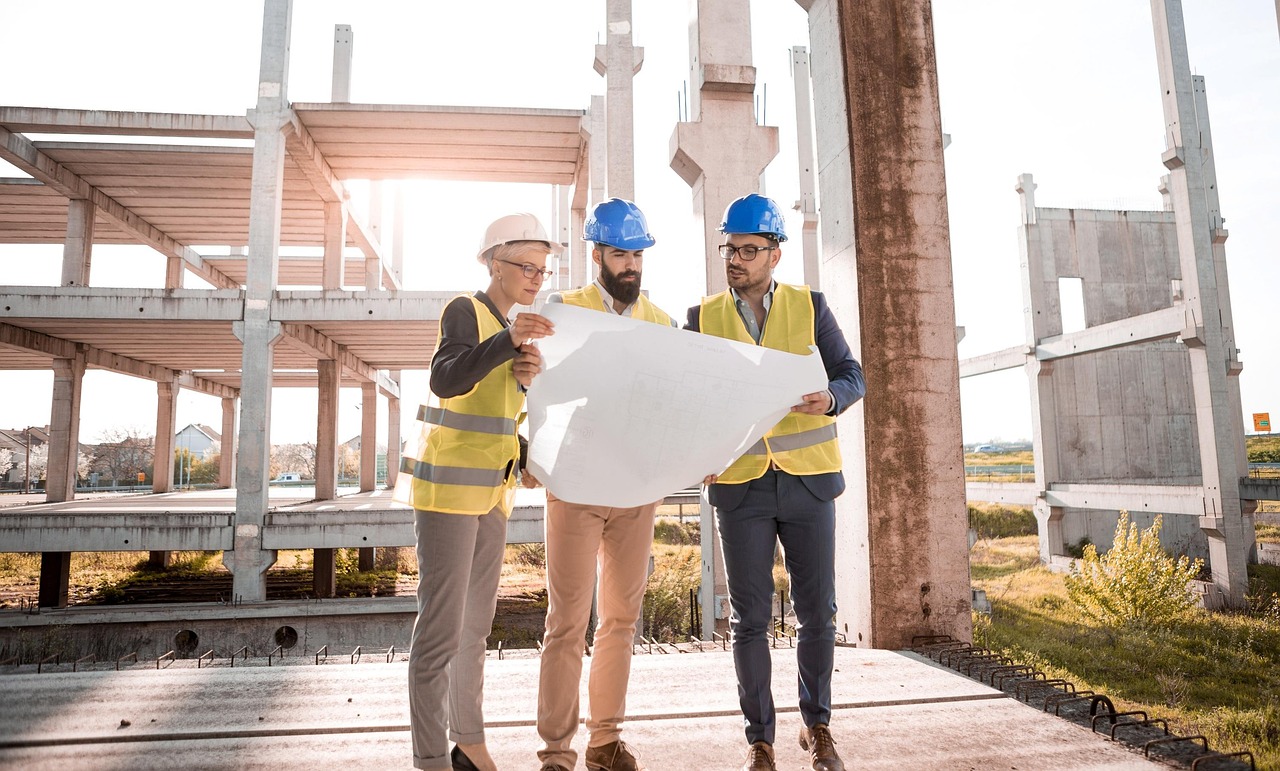 Construction crew in hard hats and safety vests reviewing building plans on a jobsite